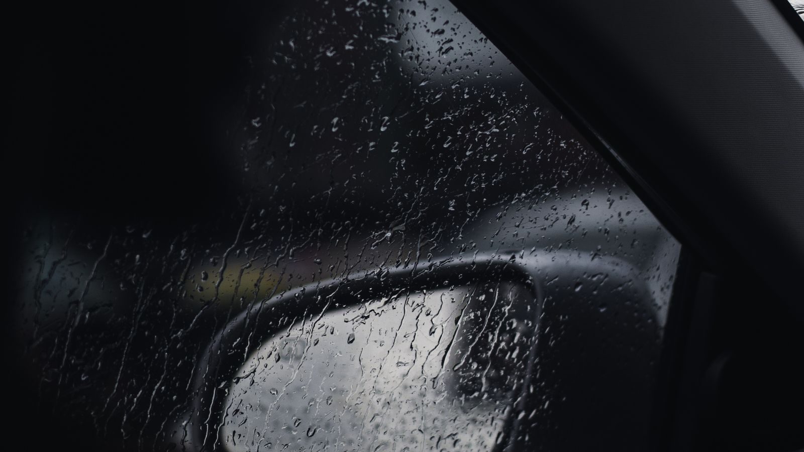Rain running down a car's side window and mirror